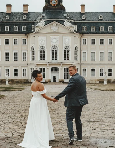 Braut und Bräutigam Hand in Hand vor dem Schloss Wermsdorf – romantische Hochzeitsfotografie in Sachsen
